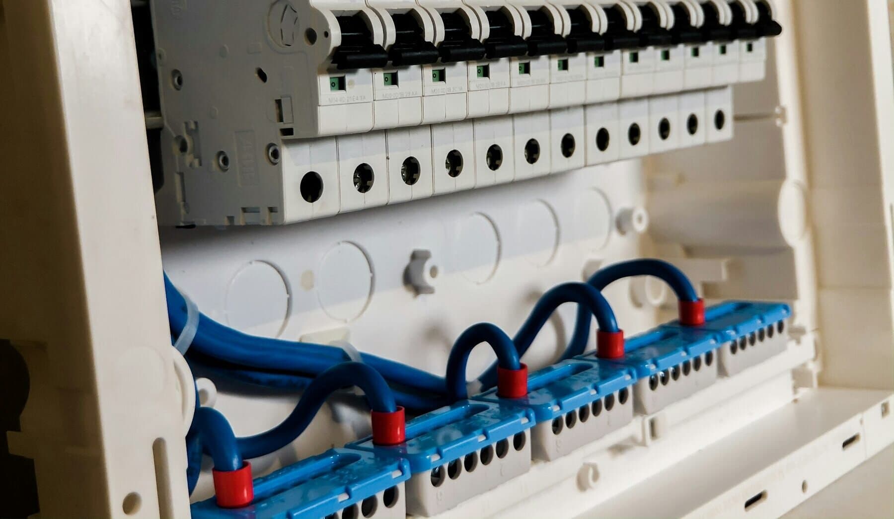 Närbild på en vit elcentral med automatsäkringar